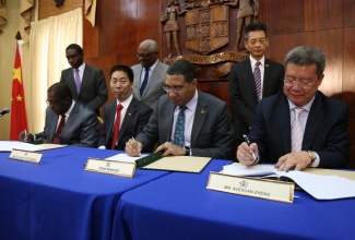 Prime Minister Andrew Holness (second right) this morning (March 9) signed a Memorandum of Understanding with China Construction of America (South America Division) for the construction of the Government of Jamaica Parliament and Government Office Oval Zone Project.  Also signing are: (L-R) Senator Ransford Braham, Chairman, UDC; Chinese Ambassador to Jamaica, His Excellency Mr. Niu Quinbao and Mr. Xuexuan Zheng, Vice President CSCEC. Looking on are: (L-R)  Dr. Damian Graham, General Manager UDC,  Dr. the Hon. Glenford Christian, UDC Board Member and Mr. Fan Jianghong, Counsellor, Economic and Commercial Counsellor Office, People’s Republic of China Embassy. 