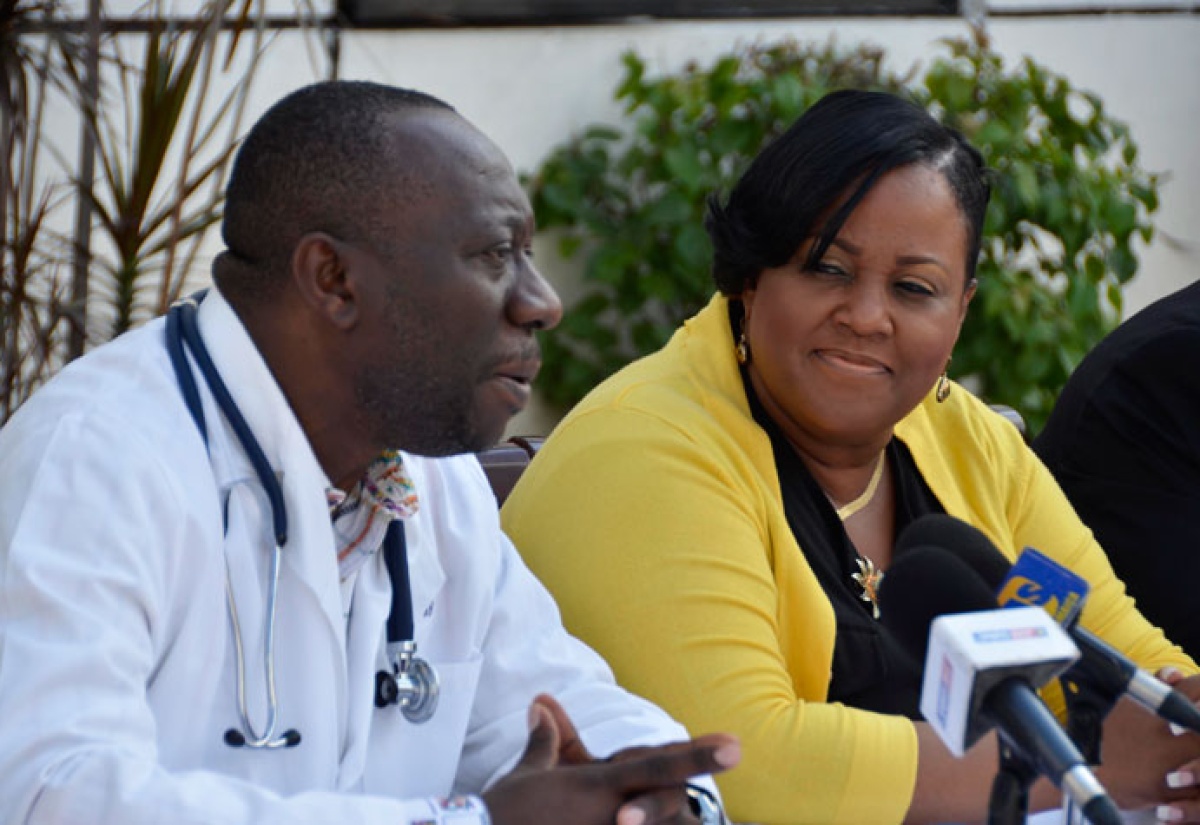 Minister with responsibility for Sport, Hon. Natalie Neita Headley (right), listens while Chief Executive Officer at the Heart Institute of the Caribbean (HIC), Professor Ernest Madu, outlines the commitment of HIC to offer free heart screening to Jamaican athletes, at a press briefing, held on April 15 at the HIC Balmoral Avenue offices in St. Andrew.