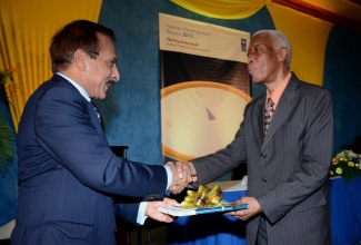 Foreign Affairs and Foreign Trade Minister, Senator the Hon. A.J Nicholson (right), is presented with a copy of the United Nations Development Programme (UNDP), Human Development Report (HDR), entitled: ‘The Rise of the South: Human Progress in a Diverse World,’ by UNDP Resident Representative in Jamaica, Dr. Arun Kashyap. Occasion was Tuesday’s (June 4) national launch of the publication at the Jamaica Pegasus Hotel, New Kingston.