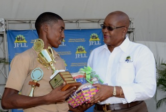 Winner of the Jamaican Foundation for Lifelong Learning’s (JFLL) poster competition, Allan Morrison (left) accepts his prize from Board Chairman of the JFLL, Audrey Hinchcliffe. The presentation was made during the staging of the JFLL’s ‘Opportunities Fair’, at Emancipation Park in Kingston on July 23.