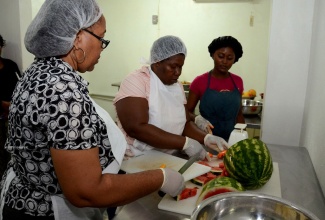 Participants from the Institute for Mobilisation, Partnership and Action for Community Transformation (IMPACT) Limited, Millicent Phillipson (right), Jane Johnson (centre) and Shanecia Hussey prepare healthy snacks to be served at several schools in the Corporate Area. The project was initially supported under the Jamaica Emergency Employment Programme (JEEP).