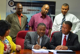 Minister of Science, Technology, Energy and Mining, Hon. Phillip Paulwell (seated centre), signs a US$2.65 million contract with Geddes Refrigeration Limited for the design, supply and retrofitting of efficient air conditioning solutions in four State entities,  at the Ministry’s New Kingston offices on  December 11. Others sharing in the moment are: Permanent Secretary in the Ministry, Hilary Alexander (seated left), Chief Executive Officer, Geddes Refrigeration Limited, Roy Lafayette (seated right); Principal Director in the Ministry, Fitzroy Vidal (standing left); Minister of State in the Ministry, Hon. Julian Robinson and Acting Project Manager, Energy Efficiency and Conservation Programme, Leon Fraser.