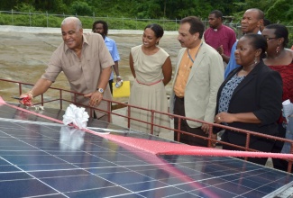 Minister of Water, Land, Environment and Climate Change, Hon. Robert Pickersgill (left), cuts the ribbon to a solar power system, to be used for operating the Pleasant Valley water catchment facility, in Clarendon, recently. Others sharing in the occasion are (from second left): Programme Manager for the Environmental Foundation of Jamaica, Allison Rangolan-McFarlane; Resident Representative for the United Nations Development Programme (UNDP), Dr. Arun Kashyap; and National Coordinator for the Global Environment Facility Small Grants Programme (GEF SGP), Hyacinth Douglas.