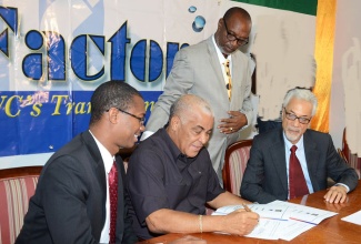 Minister of Water, Land, Environment and Climate Change, Hon. Robert Pickersgill (second left), participates in the signing of a contract for the Portmore Sewage Project at the Ministry’s New Kingston offices on December 12. Looking on are (from left): Minister of State in the Ministry of Foreign Affairs and Foreign Trade and Member of Parliament for St. Catherine East Central, Hon. Arnaldo Brown; Minister of State in the Ministry of Local Government and Community Development and Member of Parliament for St. Catherine South Eastern, Hon. Colin Fagan (standing); and Chairman and Chief Executive Officer, Surrey Paving and Aggregate Company Limited, Leslie Chang.