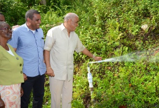 Water, Land, Environment, and Climate Change Minister, Hon. Robert Pickersgill (right), performs the symbolic commissioning of the $60 million Mile Gully/Warwick Castle water supply system in St Mary on Thursday, November 28. Sharing the moment are: President, Mile Gully/Warwick Castle Benevolent Group, Ceceline Day (left); and Member of Parliament for Western St. Mary, Joylan Silvera.