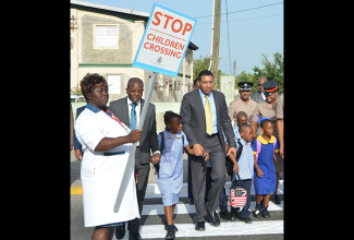 Prime Minister, the Most Hon. Andrew Holness (4th left), helps children to cross the street outside of the Seaward Primary and Junior High School on Olympic Way in St Andrew, as they began the first day of the academic year in September 2016. At 2nd left is State Minister for National Security, Hon. Pearnel Charles Jnr.