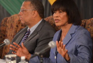 Prime Minster, the Most Hon. Portia Simpson Miller (right), addresses journalists at the post budget news conference, today (May 3), at Jamaica House, where she said the first tranche of US$207 million from the International Monetary Fund (IMF) is expected to be deposited into the Jamaican account today. At left is Finance and Planning Minister, Dr. the Hon. Peter Phillips. 