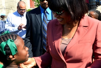 Prime Minister, the Most Hon. Portia Simpson Miller (right), engages with a student of the Hope Valley Experimental School in East Rural St. Andrew, at the official opening of the Kintyre Bridge, on December 4. The bridge was constructed at a cost of $100 million.
