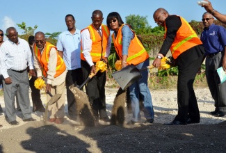 Prime Minister the Most Hon. Portia Simpson Miller (third right), breaks ground for Phase 1A of Majesty Gardens Housing Development, in South St. Andrew on March 26.  Also taking part are  National Housing Trust (NHT) Chairman, Hon. Easton Douglas (second left); Acting Managing Director, NHT, Martin Miller (fourth left); and Minister without Portfolio, Ministry of Transport, Works and Housing, Hon. Dr. Morais Guy (second right). Looking on are NHT Board Member, Vincent Morrison (left); Councillor, Greenwich Town Division, Carl Blake (third left); and Senior General Manager, Construction, NHT, Donald Moore (right).