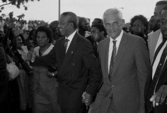 The late former President  of South  Africa, Nelson Mandela  (left), walks with  the late former Prime Minister of Jamaica,  Michael Manley, when he arrived in the island in July of 1991. Mr. Mandela died on December 5 at the age of 95. (FILE)