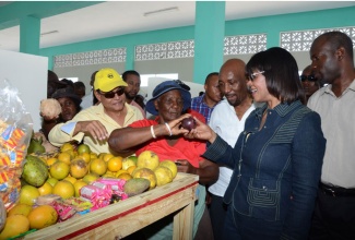 Prime Minister the Most Hon. Portia Simpson Miller (second right) admires a star apple being sold by a vendor inside the newly constructed Rocky Point Market in Clarendon on April 12, during a tour of the facility. With the Prime Minister are (from left); Minister of Local government and Community Development, Hon. Noel Arscott; Member of Parliament, South East Clarendon, Rudyard Spencer; and Mayor of May Pen, Councillor Scean Barnswell.