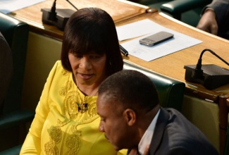 Prime Minister the Most Hon. Portia Simpson Miller (left),  in conversation with Leader of Government Business in the  House and Minister of Science, Technology, Energy and Mining, Hon. Phillip Paulwell, before making her  presentation in the 2014/15 Budget Debate in the House of Representatives on Tuesday, April 29.