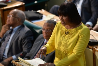 Prime Minister the Most Hon. Portia Simpson Miller (right), makes her presentation in the 2014/15 Budget Debate in the House of Representatives on Tuesday, April 29.  Seated at left  is Minister of Finance and Planning, Dr. the Hon. Peter Phillips and Minister of Transport and Works, Dr. the Hon. Omar Davies. 