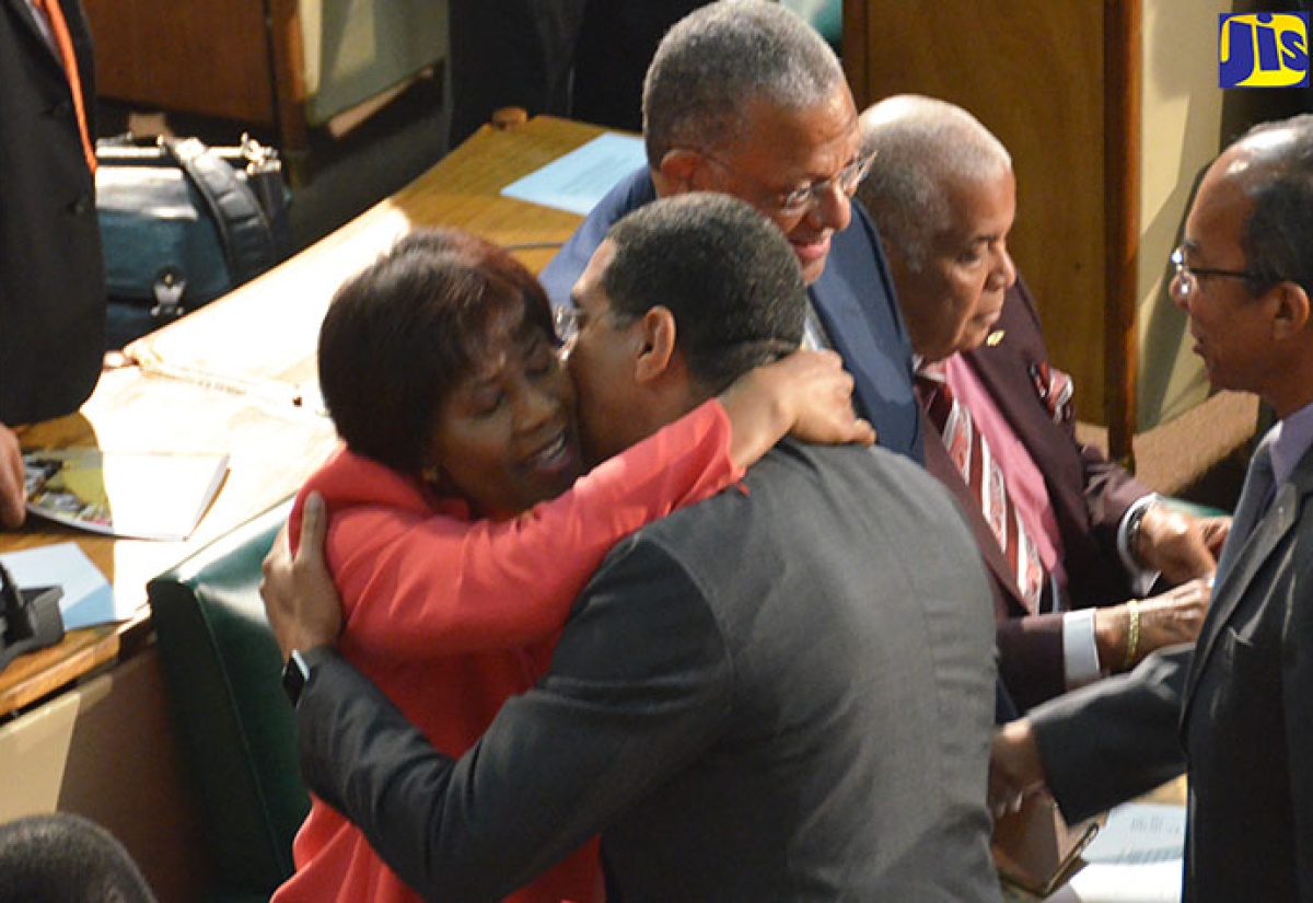 Prime Minister, the Most Hon. Andrew  Holness (second left), embraces outgoing Leader of the Opposition, the Most Hon. Portia Simpson Miller (left), following her contribution to the 2017/18 Budget Debate in the House of Representatives on March 16. It was Mrs. Simpson Miller's final budget presentation in Parliament as Opposition Leader. Shaking hands in the background (from right) are Minister without Portfolio in the Ministry of Economic Growth and Job Creation, Hon. Dr. Horace Chang and Opposition Spokesperson on Finance, Dr. Peter Phillips. Seated is Member of Parliament for North West St. Catherine, Robert Pickersgill.