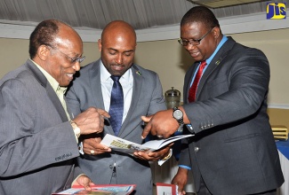 Minister of Science, Energy and Technology, Dr. the Hon. Andrew Wheatley (centre), peruses a document with (from left) Director General, National Commission on Science and Technology, Professor Errol Morrison and Executive Director of the Scientific Research Council, Dr. Cliff Riley. Occasion was the launch of the Joint Call for Applications under the Jamaica/South Africa Agreement on Scientific and Technological Cooperation, at the Terra Nova All-Suite Hotel in St. Andrew on April 19.