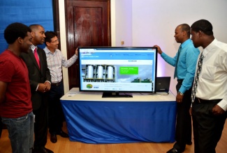 State Minister for Science, Technology, Energy and Mining, Hon. Julian Robinson (2nd left), and Chairman of the Petroleum Corporation of Jamaica (PCJ), Christopher Cargill (3rd left), look on while winners of the PCJ’s Website Development Competition, show off features of their winning design. The students, who are part of a five-member team from the University College of the Caribbean are Orane Campbell (right); and Jermaine McDonald (2nd right). Christopher Gayle (left) of the University of the West Indies, who placed second, also looks on.