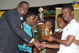 Executive Director of the Scientific Research Council (SRC), Dr. Cliff Riley (left), presents the trophy for the Most Outstanding Tertiary Institution to The Mico University College at the SRC Science and Technology Fair 2016.  The students (from left) are Shavaun Blaine, Larey Graham, Monique Reid, Rodaine Hall and John Ross Turnbull. The SRC’s Science, Technology and Wellness Fair will be held on June 16 at the Chinese Benelovent Association on Old Hope Road.