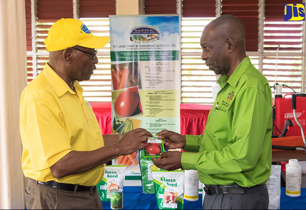 Minister without Portfolio in the Ministry of Industry, Commerce, Agriculture and Fisheries, Hon. J.C. Hutchinson (right), and Managing Director of St. Jago Farm and Hardware Supplies Limited (SJFHS), O’Brien Johnson, have a light moment with participants in the Queen’s Young Leaders Programme (QYLP) as they discuss the benefits of a knapsack sprayer. Occasion was a ceremony held at Morant Villas in St. Thomas on Tuesday (October 11), where SJFHS handed over agricultural supplies to more than 60 farmers.