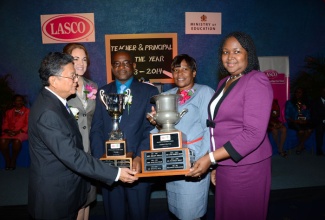 Chief Education Officer, Ministry of Education, Grace McLean (right), presents the  LASCO/Ministry of Education Teacher of the Year trophy to Janet Walters from the John Rollins Success Primary School (2nd right), while Founder and Executive Chairman LASCO Affiliated Companies, Lascelles Chin (left), hands the Principal of the Year trophy to Norman Malcolm of the Windward Road Primary and Junior High School. Occasion was the award ceremony held yesterday (Nov. 13), at the Jamaica Pegasus Hotel in New Kingston. Sharing the moment is Managing Director, LASCO Manufacturing Limited, Dr. Eileen Chin. 