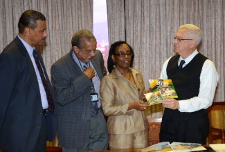 Education Minister, Hon. Rev. Ronald Thwaites (right), is presented with Vision 2030 Jamaica educational material by Communications Specialist at the Vision 2030 Jamaica Secretariat in the Planning Institute of Jamaica (PIOJ), Carmen Miller (2nd right), following his meeting on Thursday (February 13) with PIOJ representatives, at the Ministry’s offices in Kingston. Looking on (from left), are: Programme Director, Vision 2030 Jamaica Secretariat, PIOJ, Richard Lumsden; and PIOJ Director General, Collin Bullock