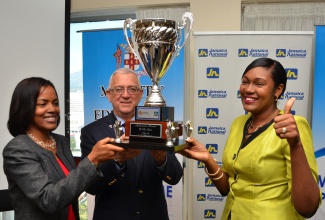 Education Minister, Hon. Rev. Ronald Thwaites (centre); and Internal Audit Executive, Jamaica National Building Society (JNBS), Tonya Grant (left), share the joy of 2014/15 Mathematics Teacher of the Year, Yanique Hall-Harriott of Christiana Leased Primary and Infant School in Manchester, after she was received the award during the presentation ceremony at the Jamaica Pegasus Hotel, New Kingston, on March 10. 