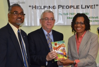 Education Minister, Hon. Rev. Ronald Thwaites (centre), is presented with a copy of the book, ‘H is for Happiness’, by co-authors and Co-Founders of  Choose Life International (CLI), Faith Thomas (right), and Dr. Donovan Thomas. Rev. Thwaites was keynote speaker at a special breakfast meeting, organised by CLI, and  held at the Knutsford Court hotel in New Kingston on February 7.