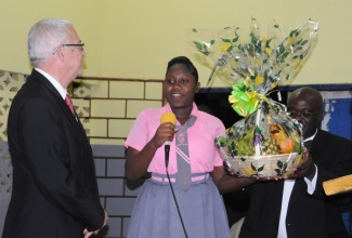 Minister of Education, Hon. Rev. Ronald Thwaites (left), about to accept a gift basket from student at the Cross Keys High School, in Manchester, Amoy Woolry, at the recent launch of a Scholarship Fund, at the school, recently. The fund is geared at assisting a past student each year with a $300,000 tuition grant.