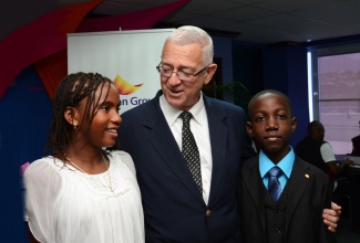 Minister of Education, Hon. Rev. Ronald Thwaites (centre), congratulates Guardian Life Limited Grade Six Achievement Test (GSAT) scholarship recipients, Michae Bradshaw (left) and Nethaneel Campbell, during Wednesday’s (August 14) awards luncheon at the company’s offices in New Kingston.