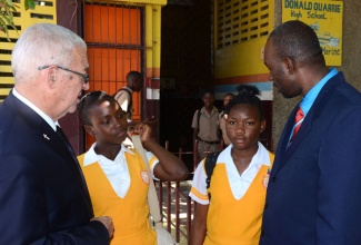 Minister of Education, Hon. Rev Thwaites (left), expresses sympathy to Donald Quarrie High School students, Danela Dyer (2nd left) and Alechia Phillips, at the death of their friend Kayalicia Simpson. At right is Principal of the School, Talbert Weir. The Minister addressed a special devotion at the school on March 5, for the late 14-year old student.
