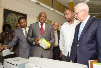 President of the Senate and Director of the University of the West Indies’ (UWI) Centre for Disability Studies, Senator Floyd Morrison (second left) has the attention of (from left) Minister of Science, Technology, Energy and Mining, Hon. Phillip Paulwell; Principal of UWI, Professor Archibald McDonald; State Minister for Science, Technology, Energy and Mining Hon. Julian Robinson; and Minister of Education, Hon. Rev. Ronald Thwaites. The Senator was explaining some of the functions of specialised equipment and software that have been acquired for seven special education institutions across the island, provided under a contract between e-Learning Jamaica Limited and the UWI Centre for Disability Studies. The more than 60 items were handed over for distribution to the various schools during a ceremony on October 13, at UWI’s Mona campus.
