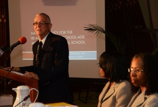 Education Minister, Hon. Rev. Ronald Thwaites (left), addresses the launch of the national policy for the reintegration of school aged mothers into the formal school system, at the Jamaica Conference Centre, Downtown  Kingston, on November 15.  Seated are: Assistant Representative, United Nations Population Fund (UNFPA), Melisa McNeil-Barrett (left), and Permanent Secretary in the Ministry, Elaine Foster Allen. 