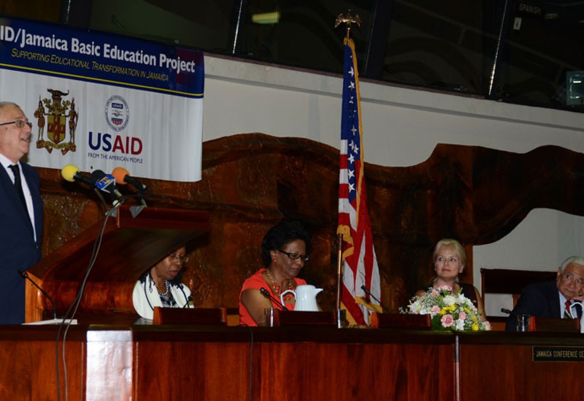 Minister of Education, Hon. Rev. Ronald Thwaites, addresses the symbolic handing over ceremony for the United States Agency for International Development (USAID)/Jamaica Basic Education Project (JBEP), at the Jamaica Conference Centre, downtown Kingston, recently. Seated (from left) are: Education Specialist, USAID, Claire Spence; JBEP Project Director, Dr. Jean Beaumont; Mission Director, USAID, Denise Herbol; and President of Juarez and Associates, Nicandro Juarez.