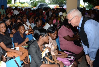 Minister of Education, Hon. Rev. Ronald Thwaites (right), listens to a concern being raised by trainee teacher of the Mico University College, Chevelle Crosdale (left), at a job fair for unemployed teachers hosted by the Ministry at its National Heroes Circle location in Kingston, August 13.  At second left is trainee teacher, Shortwood Teachers’ College, Shelly-Ann Willis. 