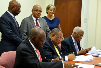 Ministers of Government sign the Trade Facilitation Memorandum of Understanding (MoU) today (June 22), at the Cabinet Office in Kingston. Seated (from left) are: Minister of Health, Hon. Dr. Fenton Ferguson; Minister of Industry, Investment and Commerce, Hon. Anthony Hylton; and Minister of Foreign Affairs and Foreign Trade, Senator the Hon. A.J. Nicholson. Overseeing the process (standing, from left) are: Trade Administrator, Trade Board Limited, Victor Cummings;  Vice Chairman, Trade Facilitation Task Force, Major (Ret’d) Richard Reese; and Chairperson, Trade Facilitation Task Force, Patricia Francis. The agreement was signed at the Cabinet Office in Kingston today (June 22). 

