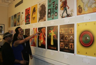 Ambassador to the United States, His Excellency Stephen Vasciannie (right), listens attentively as member of the International Reggae Poster Contest (IRPC), Kathryn Buford (centre), explains the significance of one of the posters on display at the Embassy of Jamaica.  Looking on (at left) is founder of the IRPC, Michael Thompson.  The exhibition, which was officially opened by Ambassador Vasciannie at the Embassy on  November 14,  will run for one week.  