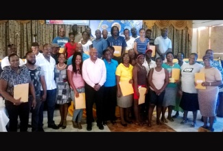 Minister Without Portfolio in the Ministry of Transport, Works and Housing , Hon. Dr. Morais Guy (6th left); and Member of Parliament for Eastern Westmoreland, Luther Buchanan (3rd left), share with proud land owners of Whitehouse, following the handing over of certificates of title on Friday, March 27. Sixty-five residents of the community and 37 others in Galloway district in Whithorn, were presented with titles under the Government’s land titling programme.