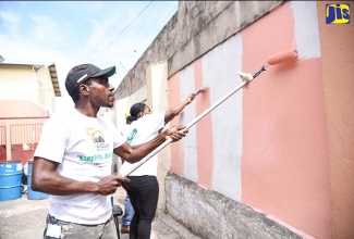 Urban Development Corporation (UDC) Chief Executive Officer, Dr. Damion Graham (foreground), paints a section of wall at Calabar Infant, Primary and Junior High School in Kingston on Labour Day, Wednesday, May 23.  In the background is recruit under the Government’s Housing, Opportunity, Production and Employment (HOPE) programme, Sandy Douglas, who is attached to the UDC.