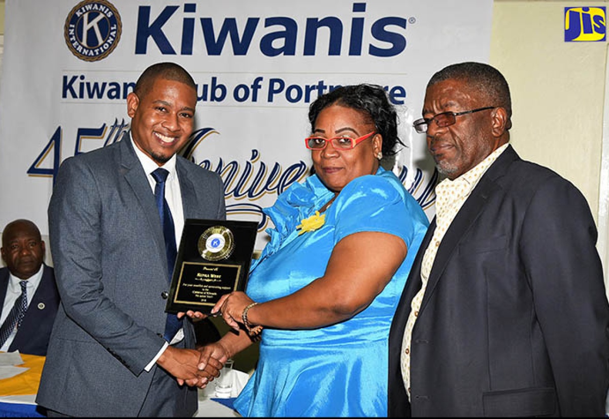 Minister of State in the Ministry of Education, Youth and Information, Hon. Floyd Green (left), presents a plaque to Advisor to the  Kiwanis Club of Portmore, Miss Runka West (centre), for her dedication to children. Occasion was the Club’s 45th anniversary celebration held on May 22 at the Four Seasons Hotel in St. Andrew.  At right is Distinguished President of the organisation, Don Mullings.
