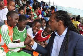 State Minister in the Ministry of Culture, Gender, Entertainment and Sport, Alando Terrelonge (right), exchanges greetings with Naggo Head Primary School athlete, Dushawn Green (left), as his schoolmates look on. Occasion was the official opening ceremony for the 38th Institute of Sports (INSPORTS) Primary School Athletics Championships on Friday, May 11 at the National Stadium in Kingston. 