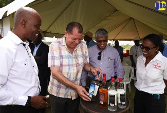 Minister of Industry, Commerce, Agriculture and Fisheries, Hon. Audley Shaw (centre),  examines the label of a Monymusk Rum during a tour of National Rums of Jamaica Limited and Clarendon Distillers Limited in Lionel Town, Clarendon, on Thursday (June 14). Observing (from left) are Chief Executive Officer, National Rums of Jamaica, Winston Harrison; Chairman of the Board of Directors, Komal Samaroo; and Chief Financial Officer, Martha Miller. 

