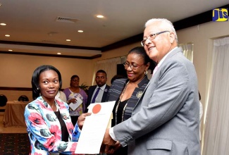 Minister of Justice, Hon. Delroy Chuck (right), hands over the instrument of office to Elizabeth Miller at the swearing-in ceremony for justices of the peace (JP) for St. Andrew at The Jamaica Pegasus hotel in New Kingston on Sunday (June 3). Sharing the moment is Custos Rotulorum for the parish, Dr. Patricia Dunwell.