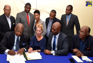 Science, Energy and Technology Minister, Dr. the Hon. Andrew Wheatley (seated second right), observes as Director of the National Foundation for the Development of Science and Technology (NFDST), Dr. Conrad Douglas (seated left), and Chief Executive Officer (CEO) of the Jamaican Medical Cannabis Corporation (JMCC) Limited, Diane Scott (second left), sign a memorandum of understanding (MOU) at the Courtleigh Hotel and Suites in New Kingston on June 25. Standing (from left) are: Scientist and Entrepreneur, Dr. Henry Lowe; Executive Director of the Scientific Research Council (SRC), Dr. Cliff Riley; Director of Research at the National Commission on Science and Technology (NCST), Dr. Aisha Jones; Director of the Caribbean Genetics, Professor Wayne McLaughlin; Botanist at the Institute of Jamaica, Keron Campbell; and Director General of the NCST, Professor Errol Morrison.

