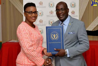 Education, Youth and Information Minister, Senator the Hon. Ruel Reid (right), presents participant in the National College for Educational Leadership (NCEL) Aspiring Principals Programme,  Sophia Brown Sinclair, with her certificate during the graduation ceremony held on June 28 at the Mona Visitors’ Lodge at the University of the West Indies (UWI), Mona Campus, in Kingston. The programme provides a standard credential, the Professional Qualification for Principalship (PQP), to which the Ministry of Education and school Boards refer before authorising the hiring of principals of public schools.