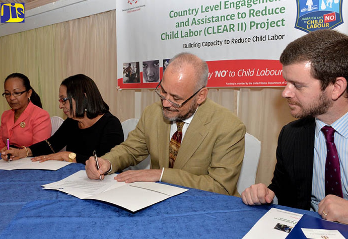 Minister of Labour and Social Security, Hon. Shahine Robinson (second left) and Senior Director, Civil Society and Education at Winrock International, David Dobrowolski (second right), sign a Memorandum of Understanding (MOU) at the launch of the Country Level Engagement and Assistance to Reduce Child Labour (CLEAR II) Project in Jamaica on Tuesday (June 26), at the Terra All-Suite Nova Hotel in St. Andrew. Observing are Permanent Secretary, Ministry of Labour and Social Security,  Colette Roberts Risden (left); and Political/Economic Officer, United States Embassy Jamaica, Daniel Walker. 
 
                                                                                                                 
