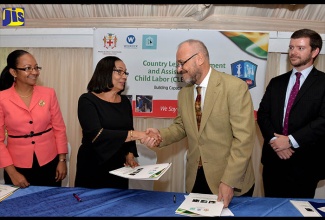 Minister of Labour and Social Security, Hon. Shahine Robinson (second left), shakes hands with Senior Director, Civil Society and Education at Winrock International, David Dobrowolski (second right) at the launch of the Country Level Engagement and Assistance to Reduce Child Labour (CLEAR II) Project in Jamaica on Tuesday (June 26) at the Terra Nova All-Suite Hotel in St. Andrew. Looking on are Permanent Secretary, Ministry of Labour and Social Security,  Colette Roberts-Risden (left) and Political/Economic Officer, United States Embassy,  Daniel Walker. 