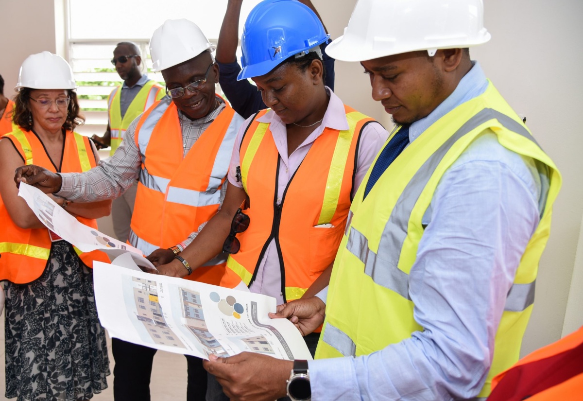 State Minister for Education, Youth and Information, Hon. Floyd Green (right), examines building plans for Transitional Living Complex for Children in State  located at 24 Lady Musgrave Road in Kingston during a tour on Thursday (June 7).  Others (from left) are Deputy Principal of the University of the West Indies (UWI) Open Campus, Professor Julie Meeks; Programme Management Specialist for the United States Agency for International Development (USAID), Jamaica, Kenneth Williams; and Construction Technician for the project, Marsha Gaye-Wright. 