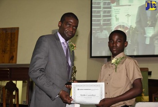 President of the Ackee Tree Group, Hopeton Brandford (left), presents a scholarship to Malik Carridice of Porus Primary School in Manchester on Saturday, July 7 at Trinity Baptist Church in Porus, Manchester.