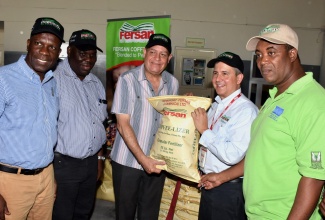 Minister of Industry, Commerce, Agriculture and Fisheries, Hon. Audley Shaw (third left), is presented with a bag of coffee fertilizer by Managing Director, Newport-Fersan Jamaica Limited (NFJ), Dennis Valdez (second right) during a symbolic handing over ceremony at NFJ’s Wherry Wharf Complex location in Kingston on Friday (July 13).  Also pictured (from left) are: outgoing President of the Jamaica Agricultural Society (JAS), Norman Grant; Permanent Secretary in the Ministry of Industry, Commerce, Agriculture and Fisheries, Donovan Stanberry; and Chief Executive Officer, Rural Agricultural Development Authority (RADA), Peter Thompson. The product, called ‘coffee-lizer’, is among the over 28,000 bags being distributed to farmers islandwide under the Fertilizer Assistance Supplies and Training (FAST) Programme which was established by the Agriculture Ministry last year.