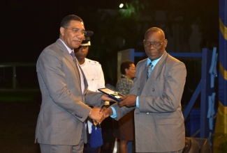 Prime Minister the Most Hon. Andrew Holness, (left) presents Retired Principal of Campbell’s Castle Primary and Infant School, Rev. Owen Lambert (right) with the Prime Minister’s Medal of Appreciation for Service to Education at the awards ceremony held on the lawns of Jamaica House on June 27.