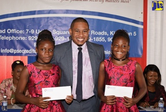 Minister of State in the Ministry of Education, Youth and Information, Hon. Floyd Green (centre), shares a moment with twins Renehia (left) and Tenehia Currie after presenting them with education grants during the Public Sector Employees Co-operative Credit Union's Grade Six Achievement Test (GSAT) awards ceremony at the St. Stephen’s United Church, Cross Roads, Kingston, on Wednesday (Aug. 15). A total of 74 students received education grants totalling $1 million from the credit union.